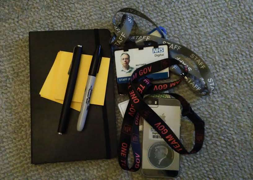 Notebook, sticky notes, Sharpie marker, fountain pen, two door entry cards and an iPhone SE