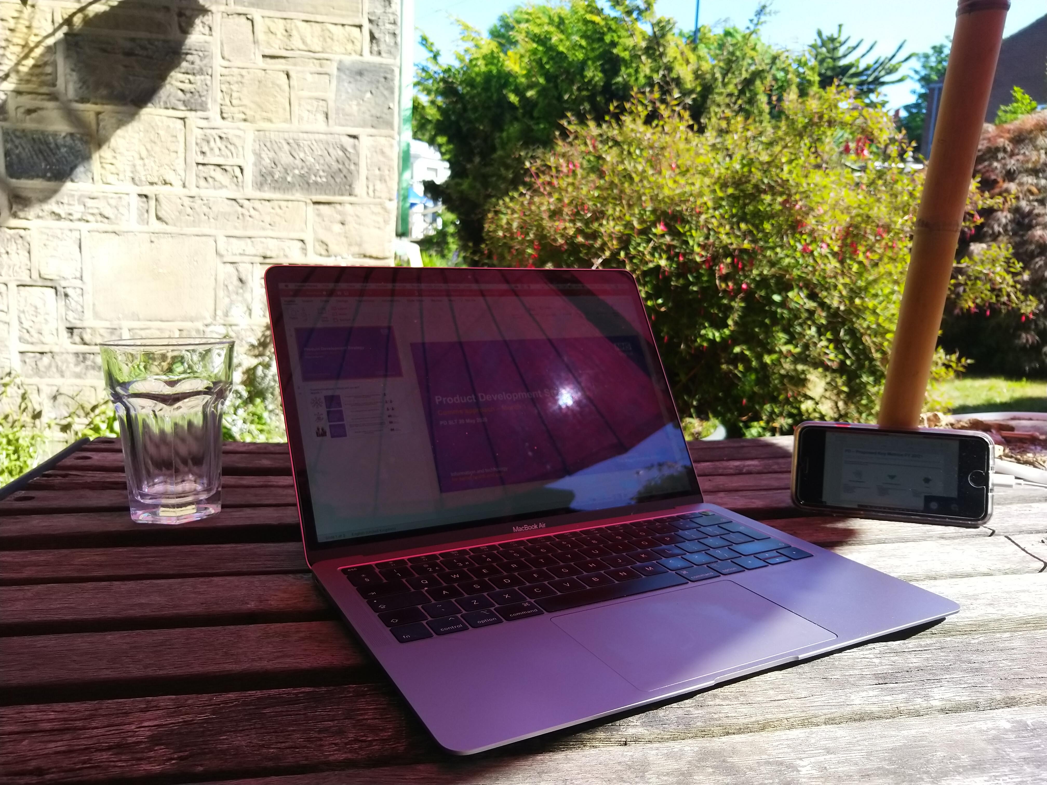 Sunny day, outdoor table, glass of water, Macbook Air, iphone