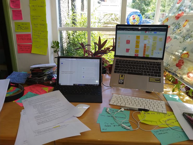 Two laptops on desk surrounded by sticky notes and papers