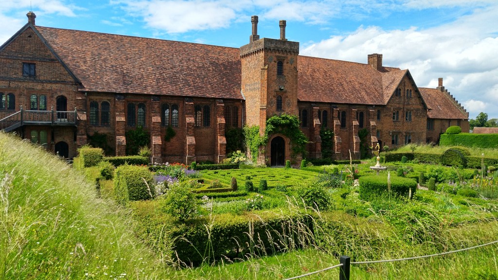 Red brick, red tile-roofed 16th Century palace with garden including box hedges, grasses and flowers