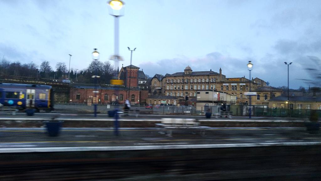 Railway platform with motion blur in foreground, Victorian mill town in background