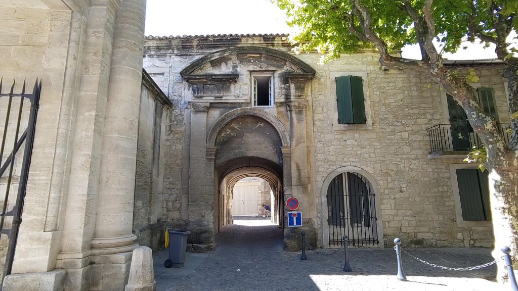 Arched gateway through a building with off-centre window above