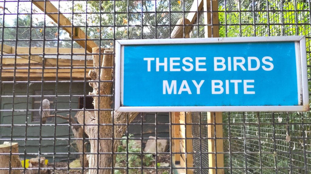 Sign fixed to wire fence that reads 'THESE BIRDS MAY BITE'