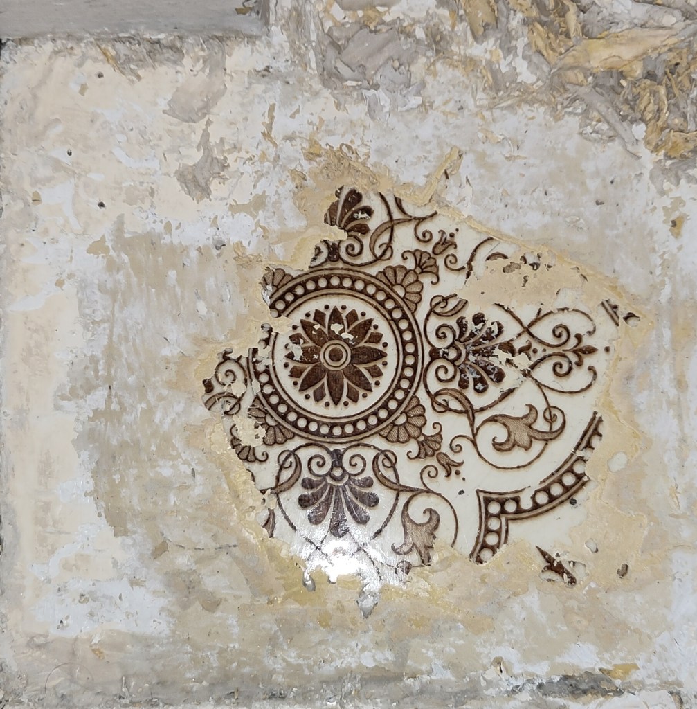 An ornate patterned tile emerging underneath layers of paint