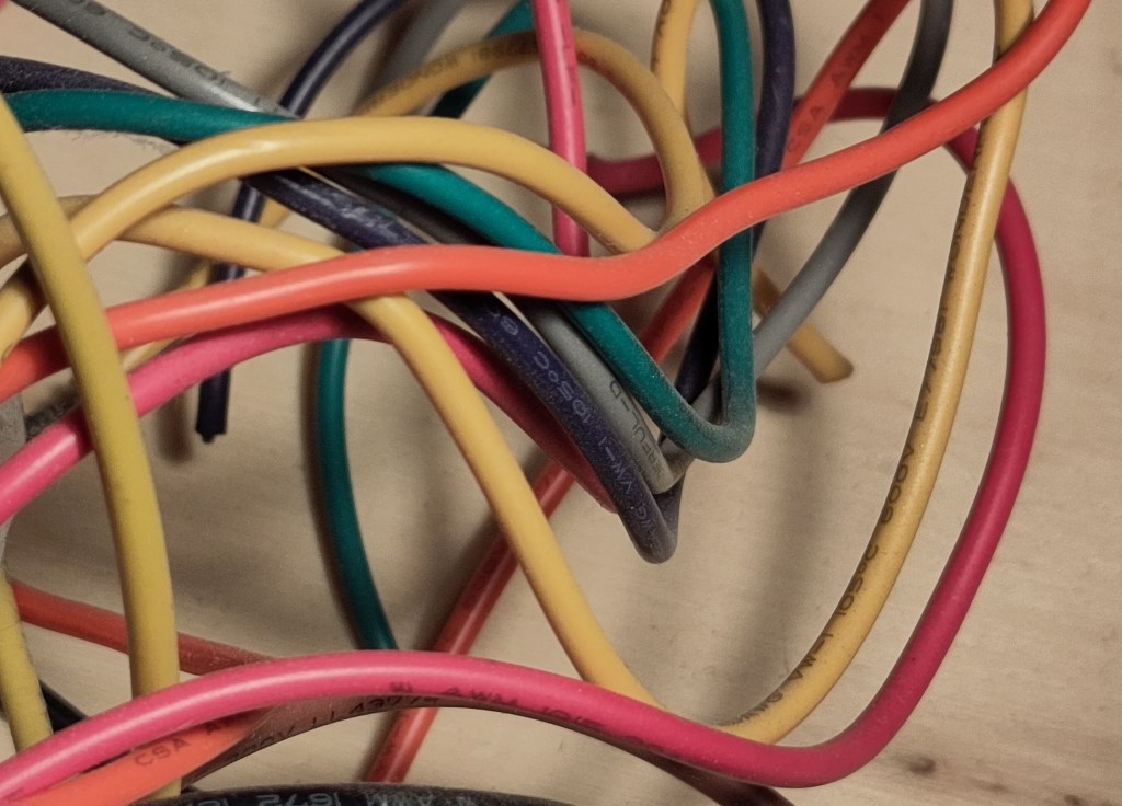 A close-up of a tangle of colourful wires on a wooden desktop